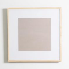 a white and beige square in a wooden frame hanging on a wall above a toilet