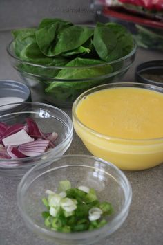 bowls filled with food sitting on top of a counter next to salad greens and onions