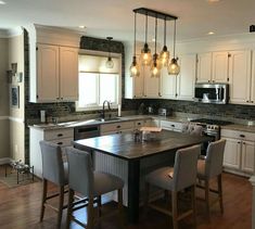 a kitchen with white cabinets and an island in the middle, surrounded by stools