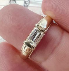 a close up of a person's hand holding a ring with an emerald stone