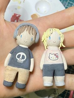 two little dolls are sitting on someone's hand