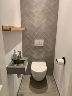 a bathroom with a toilet, sink and towel dispenser on the wall