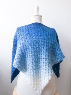 a blue and white knitted shawl sitting on top of a mannequin