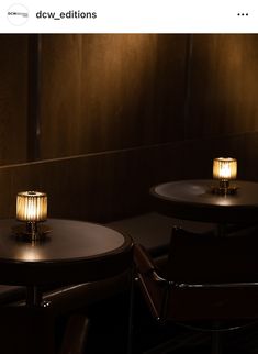 two lit candles sitting on top of wooden tables