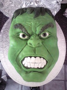 a close up of a cake with a green face on it's head and tin foil around its mouth