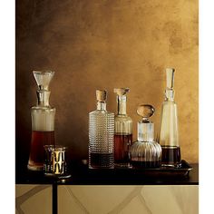 an assortment of vases on a table in front of a brown wall with gold paint