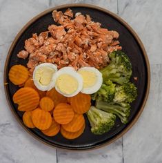 a plate with hard boiled eggs, carrots and broccoli on it sitting on a marble surface