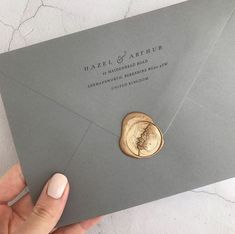 a person holding an envelope with a wax stamp on it