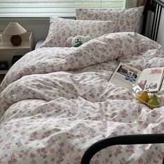 a bed with white and pink flowers on it, next to a window sill