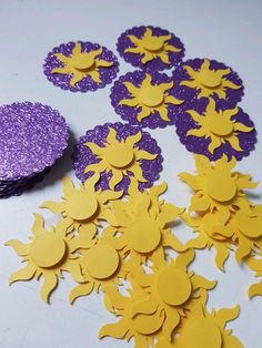 purple and yellow paper cut outs sitting on top of a table