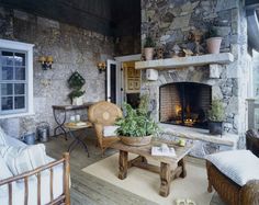 a living room filled with furniture and a fire place next to a stone wall covered in potted plants