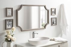 a bathroom with a sink, mirror and pictures on the wall above it is shown