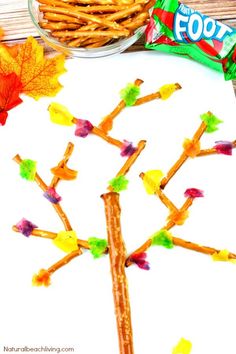 a tree made out of pretzels next to a bowl of candy and leaves