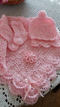 a pink crocheted sweater and hat sitting on top of a table