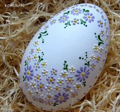 an easter egg decorated with flowers and daisies in some straw on top of hay