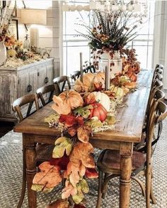 a dining room table decorated with fall leaves and pumpkins for the centerpiece on display