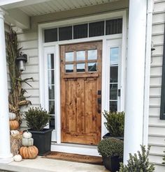 a wooden door sitting on the side of a white house next to potted plants