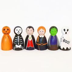 a row of wooden toy figurines with halloween characters painted on the faces and hands