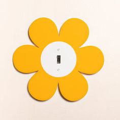 a yellow flower shaped light switch plate on a white wall with an electrical outlet in the center