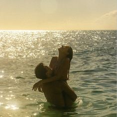 two people are in the water and one person is holding his head out to kiss