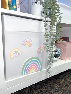 a white book shelf filled with books next to a potted plant and disco ball