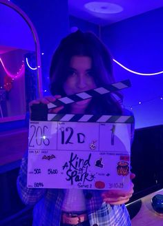 a woman holding up a clapper board in front of her face with the words kid stuff written on it