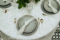 the table is set with silver and gold place settings, napkins, and flowers