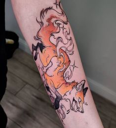 a woman's arm with an orange and black tattoo design on the left forearm