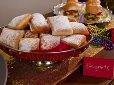 a bowl filled with sugar covered pastries on top of a table next to other desserts