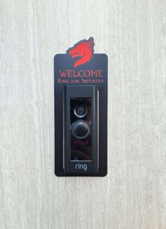 a black door handle on a white wall with a red and black sign that says welcome