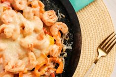 a close up of a plate of food with pasta and cheese on it next to a fork