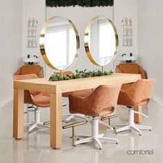 a dining room table with four chairs and two mirrors on the wall above it that have plants in them