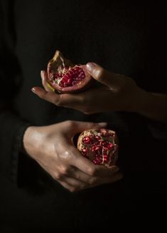 two hands holding pomegranates in the dark