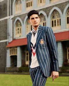 a man in a suit and tie standing on the grass near a building with windows