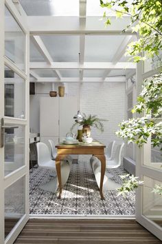 an open door leading to a dining room with white chairs and a table in the middle