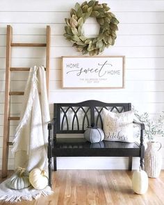 a wooden bench sitting in front of a white wall with a wreath on top of it