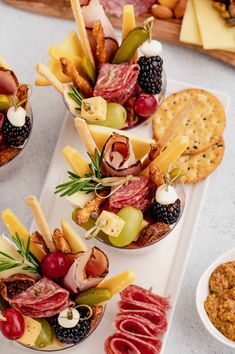 several appetizers are arranged on a platter with crackers and cheeses