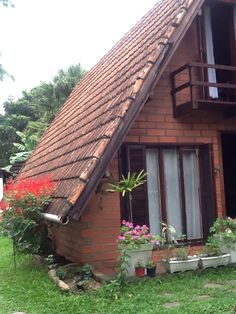 a red brick house with flowers and plants in the window boxes on the front lawn