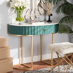 a green and gold console table with white flowers on the top, next to a mirror