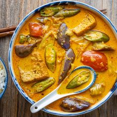 a bowl filled with curry and vegetables next to rice