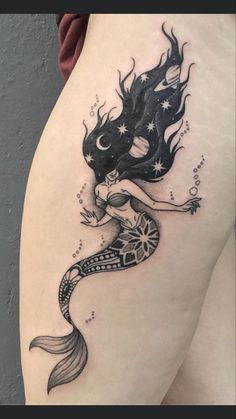 a woman's thigh with a mermaid tattoo on it