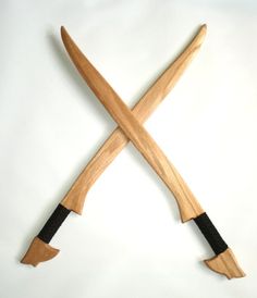 two crossed wooden knives with black handles on a white background, one in the shape of an x