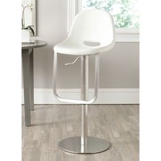 a white chair sitting on top of a wooden floor next to a table and window