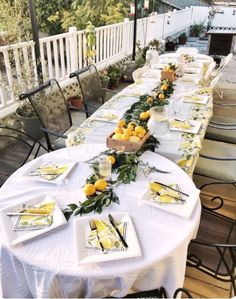 a long table is set up with lemons and greenery for an outdoor party