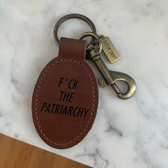 a leather keychain with the words f k the patriarchy on it