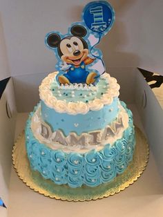 a blue and white mickey mouse cake in a box with an air balloon on top