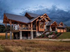 a large house sitting on top of a lush green field next to tall grass covered hillside