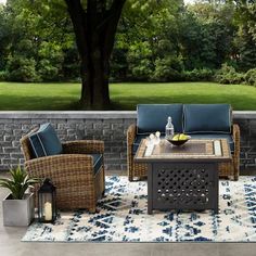 the patio furniture is set up outside by the tree and grass area with blue cushions