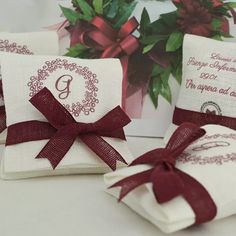 three white towels with red ribbon tied around them on a table next to a card