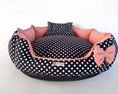 a black and white polka dot dog bed with pink bows on the front, sitting on a white surface